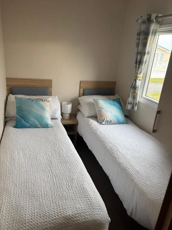 two beds in a small room with a window at Beach life in Lossiemouth