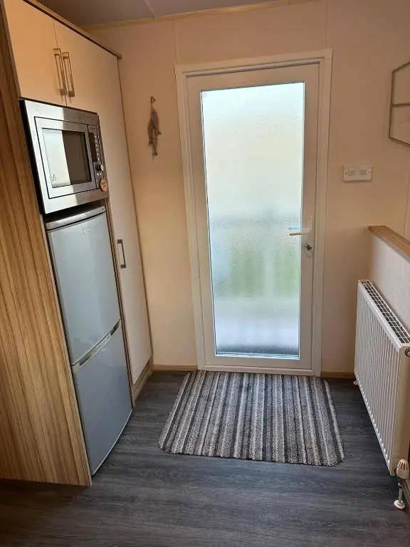 a room with a refrigerator and a large window at Beach life in Lossiemouth