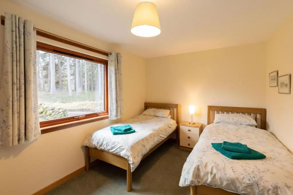 two beds in a room with a window at Aonach in Kingussie