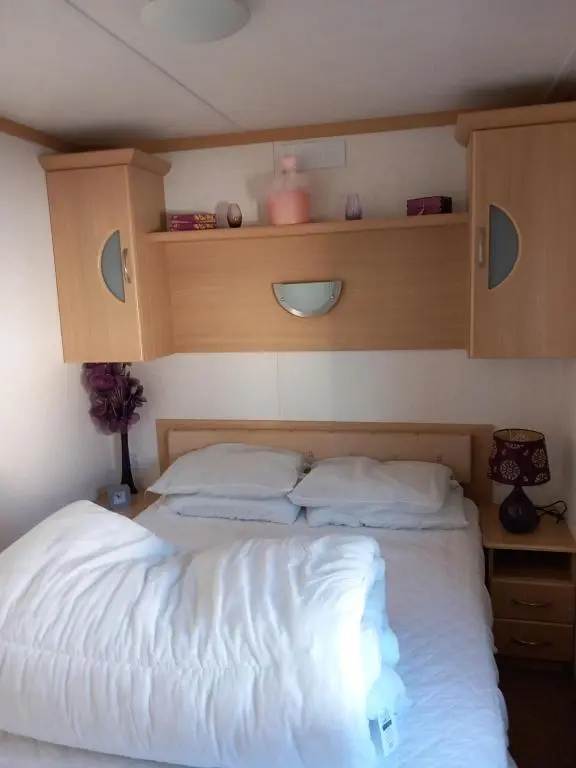 a bedroom with a white bed with a wooden headboard at Melody Brooks Caravan Park Caravan number 22 in Portknockie
