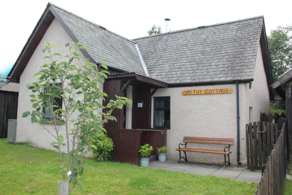 a building with a bench in front of it at Smithy Cottage in Strathdon