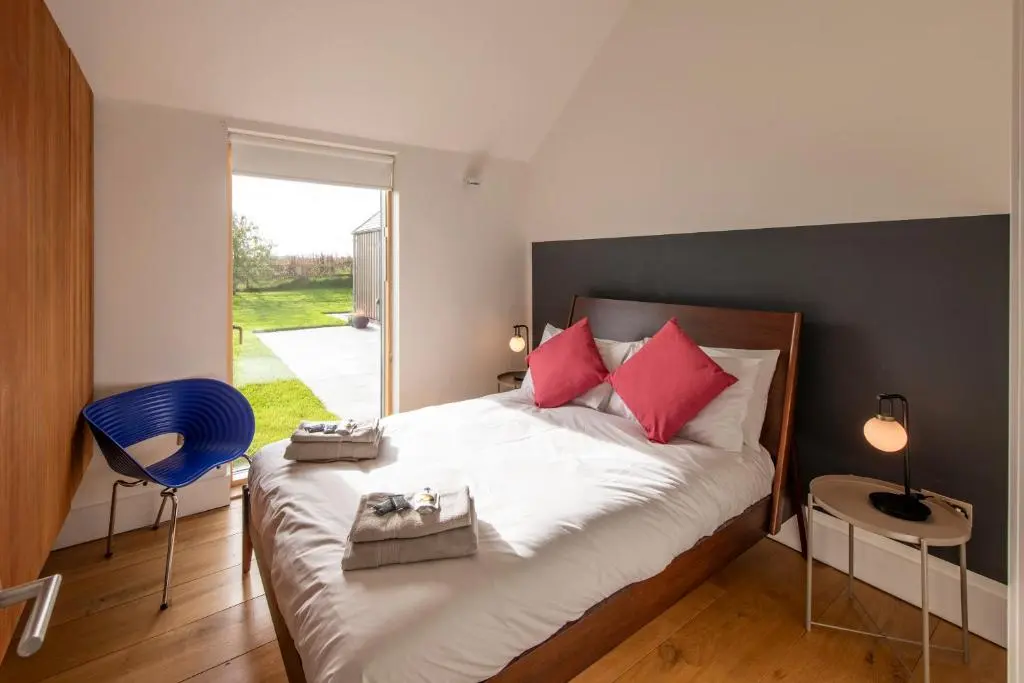 a bedroom with a large bed with red pillows at Architect Designed Lodge in Dunecht