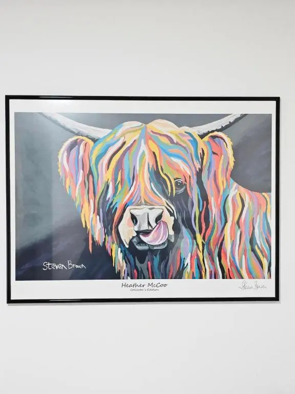 a painting of a colorful dog in a black frame at Serviced Apartment - Aberdeen in Dyce
