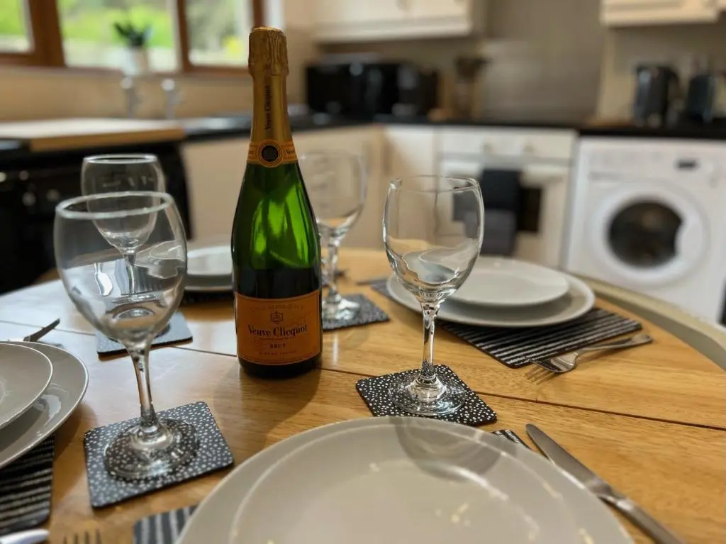 a bottle of wine sitting on a table with glasses at Birchwood Cottage in Tore