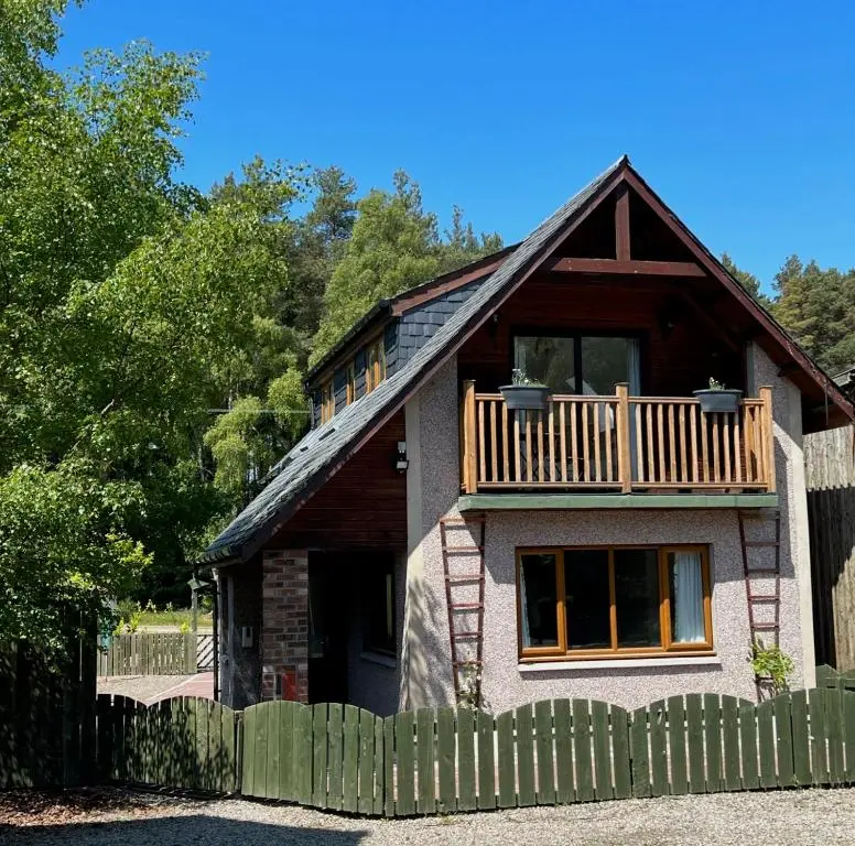a small house with a balcony and a fence at Birchwood Cottage in Tore