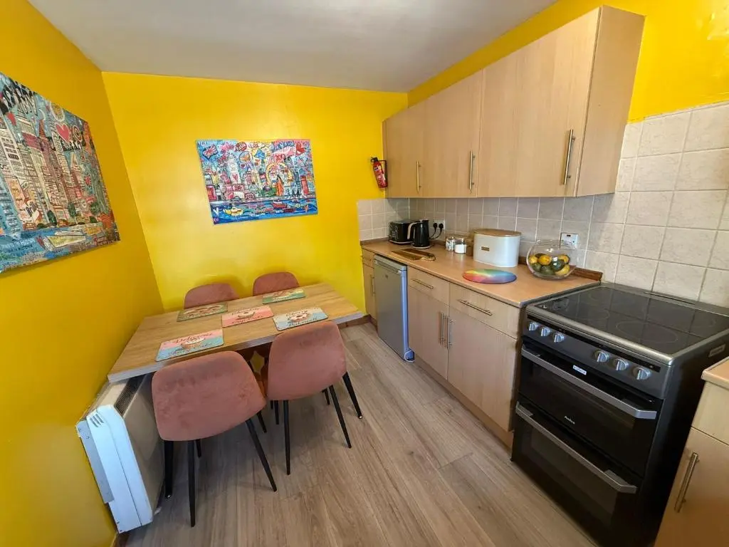 a small kitchen with yellow walls and a table and chairs at Old Dairy in Tain