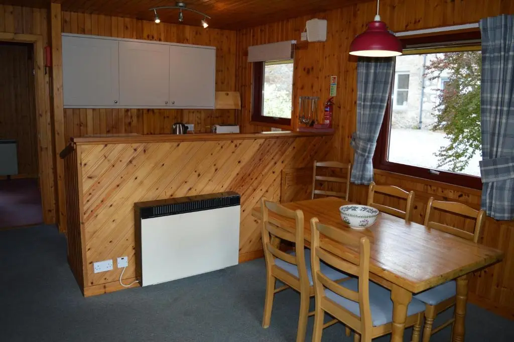 a kitchen and dining room with a wooden table and chairs at Reuben's Highland Retreat - Speyside in Carrbridge