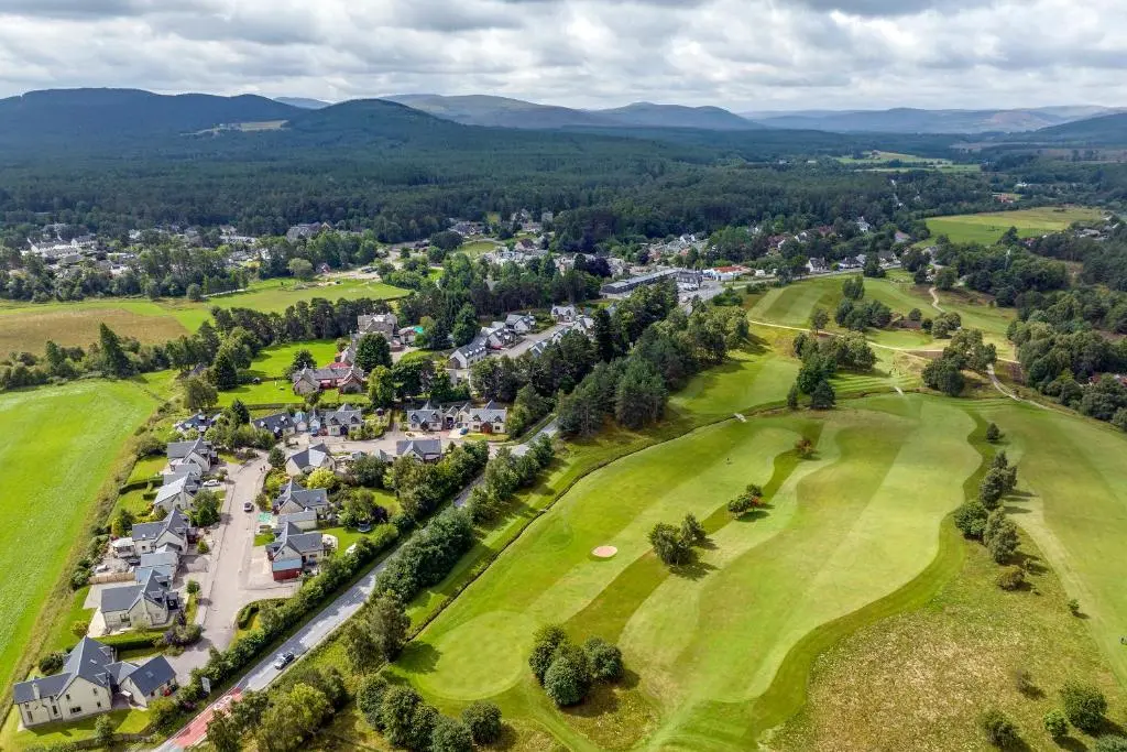 an aerial view of a golf course with houses and trees at Reuben's Highland Retreat - Speyside in Carrbridge