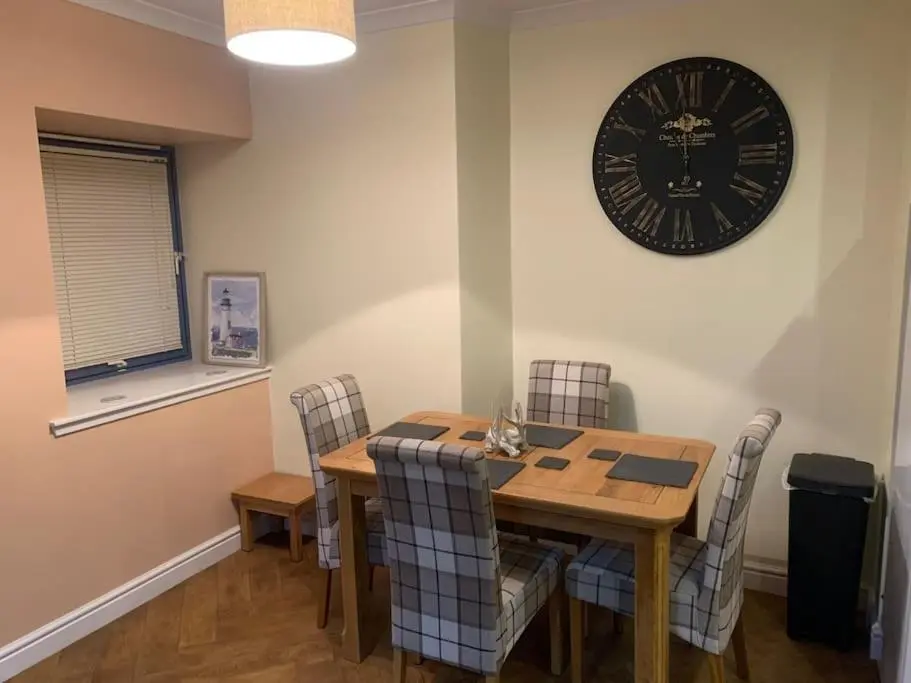 a dining room with a table and a clock on the wall at The old post office in Golspie