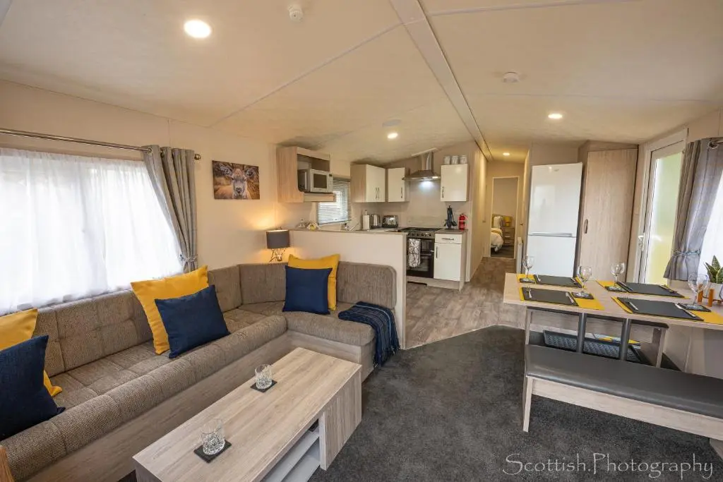 a living room with a couch and a kitchen at Highland Chalet - Peaceful Stay near Dornoch in Dornoch