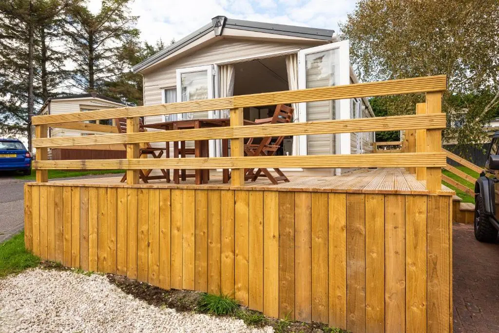 a wooden fence in front of a house at Highland Chalet - Peaceful Stay near Dornoch in Dornoch
