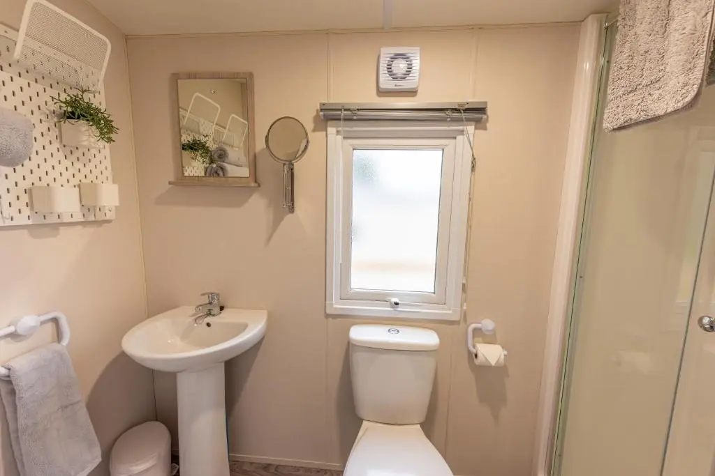 a bathroom with a toilet and a sink and a window at Highland Chalet - Peaceful Stay near Dornoch in Dornoch