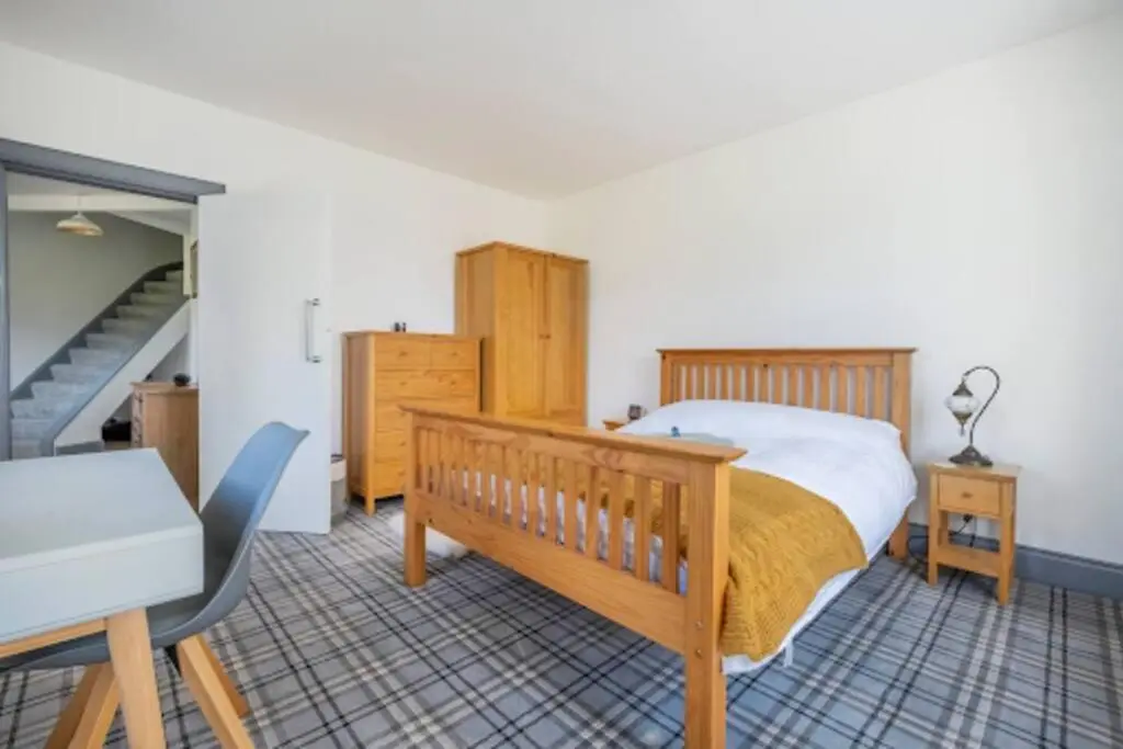 a bedroom with a wooden bed and a staircase at Cosy Hygge/ Scottish themed home by Loch Ness in Fort Augustus