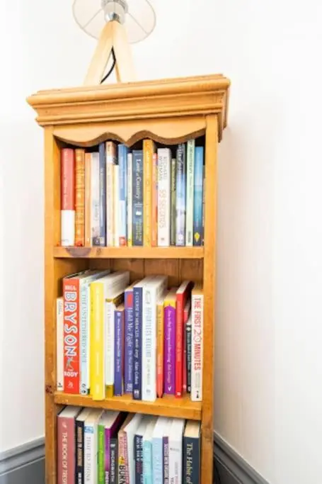 a book shelf filled with books next to a wall at Cosy Hygge/ Scottish themed home by Loch Ness in Fort Augustus