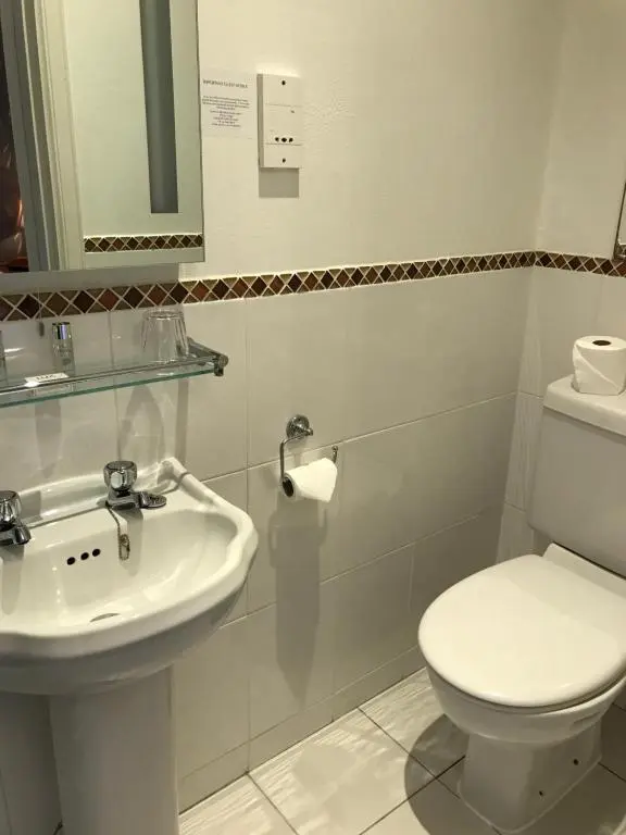 a bathroom with a white toilet and a sink at West End Guest House in Elgin