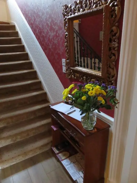 a vase of flowers on a dresser with a mirror at West End Guest House in Elgin
