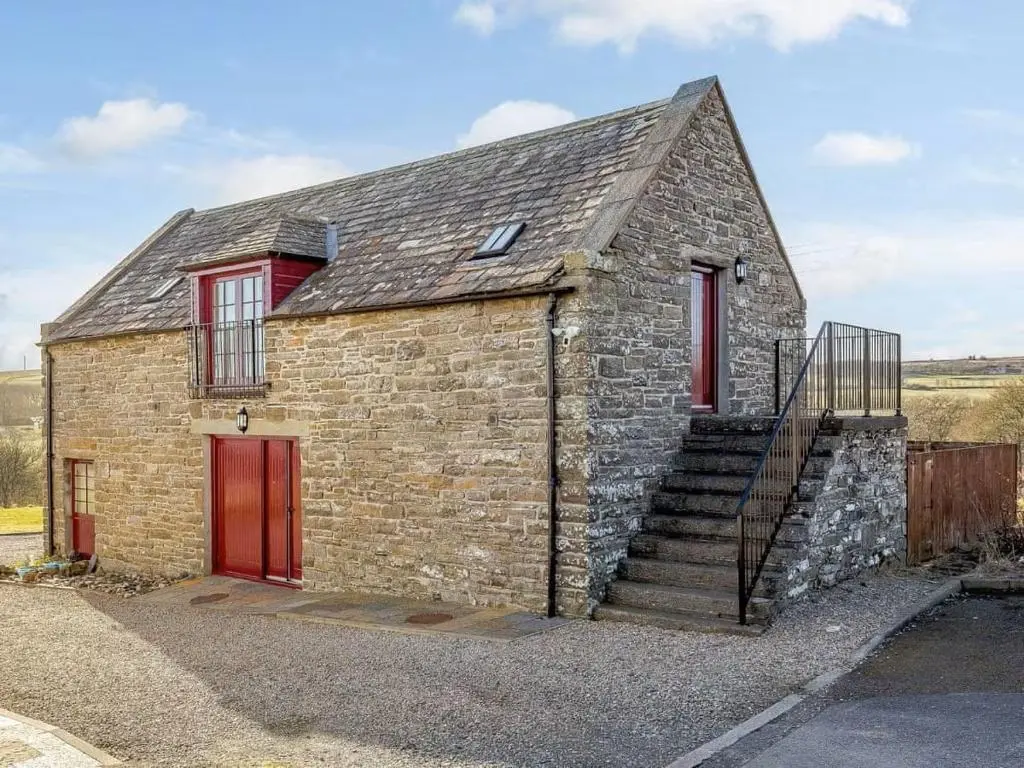 an old brick house with red doors and stairs at Craiglea Barn in Latheron