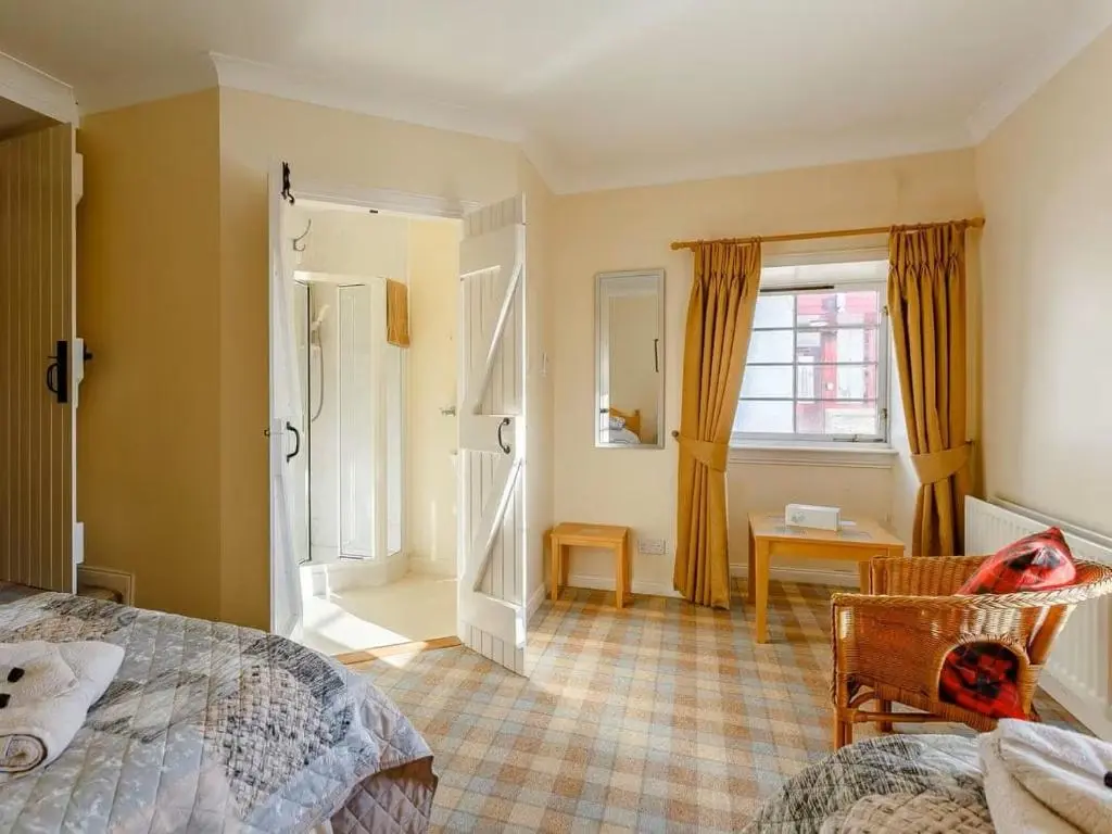 a bedroom with a bed and a table and a window at Craiglea Barn in Latheron