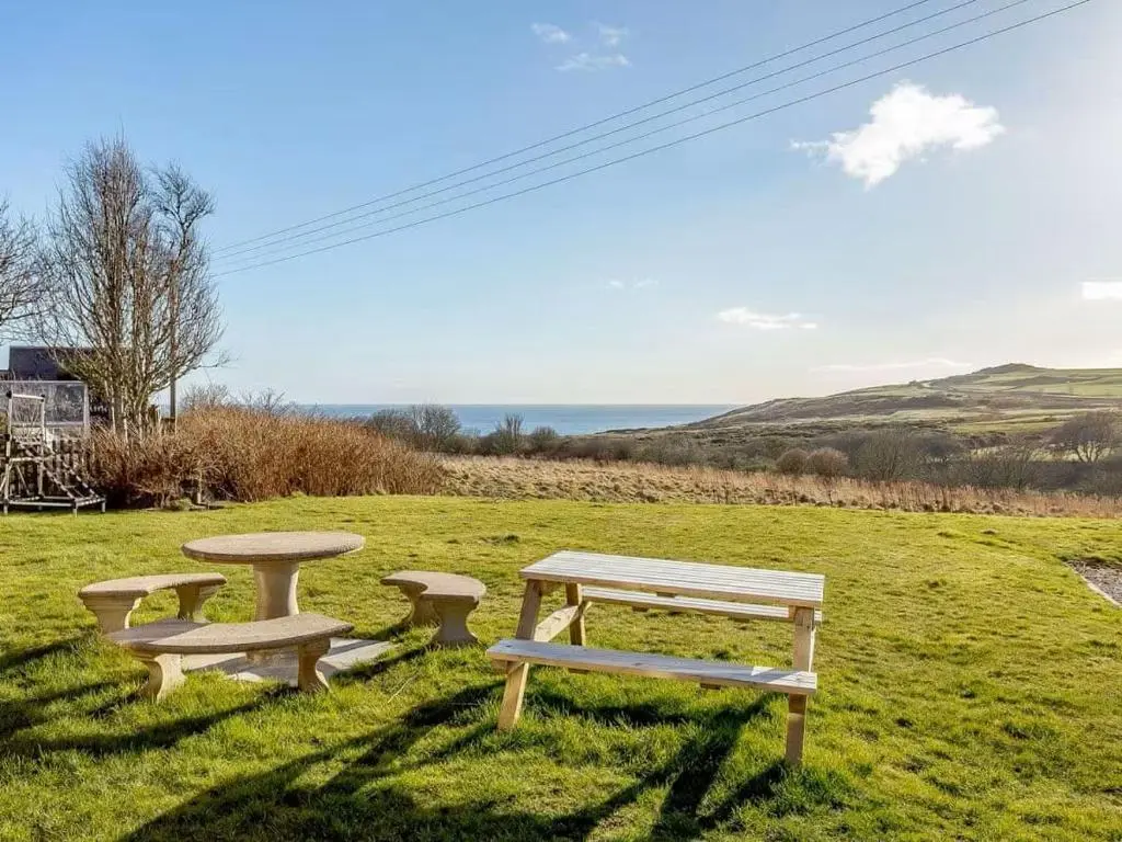 a picnic table and two benches in a field at Craiglea Barn in Latheron
