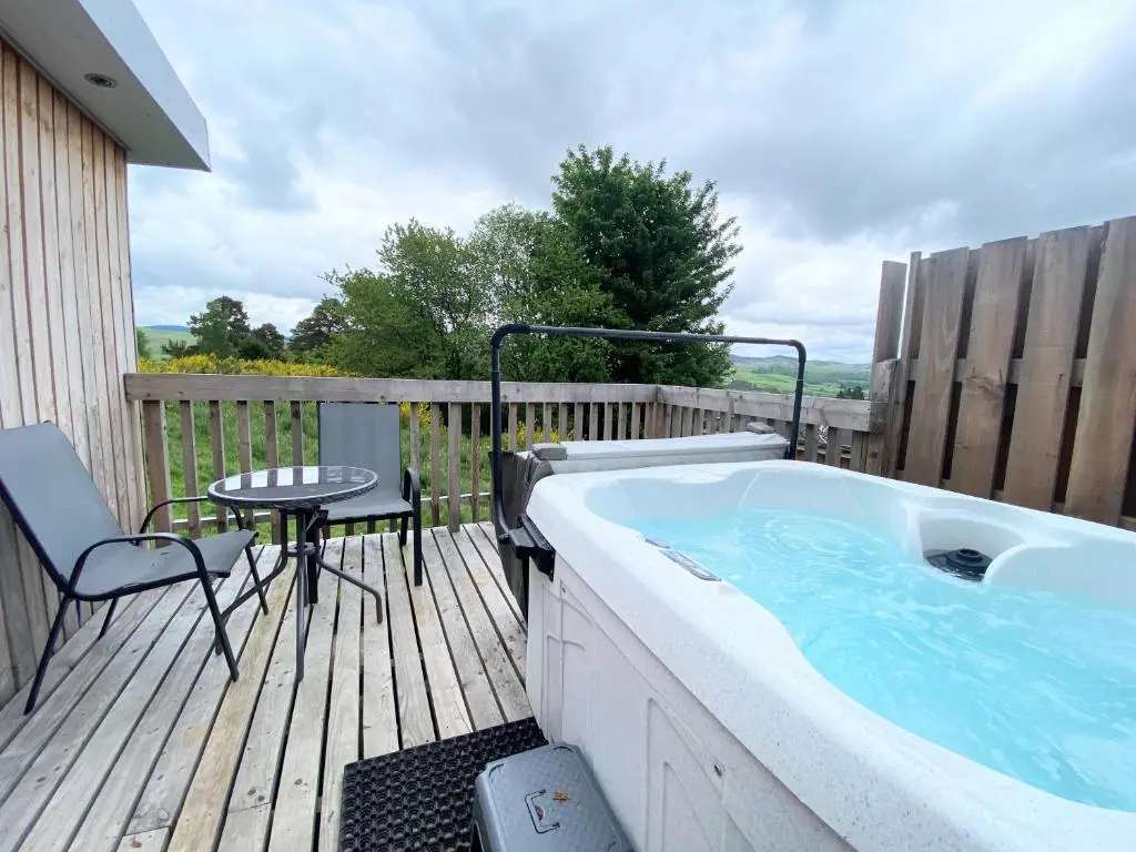 a hot tub on a deck with a table and chairs at Kaoglen Lodge - Fawn Pod - Hot Tub - Dogs - Pitlochry - Luxury in Blairgowrie