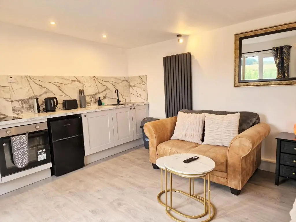 a living room with a couch and a table at Kaoglen Lodge - Fawn Pod - Hot Tub - Dogs - Pitlochry - Luxury in Blairgowrie