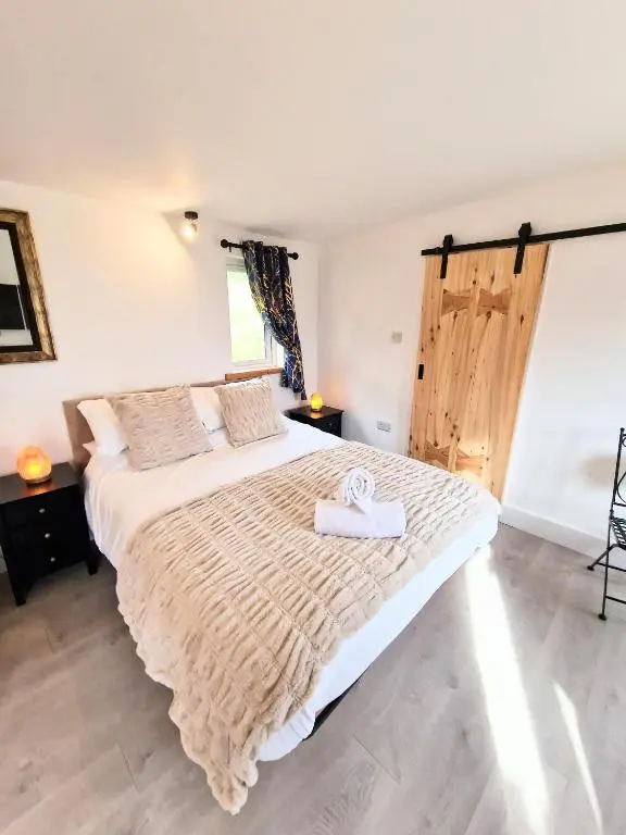 a bedroom with a large bed with a wooden door at Kaoglen Buck Pod - Hot Tub - Dog Friendly in Blairgowrie
