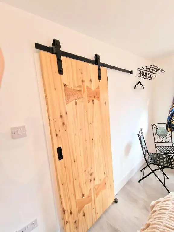 a sliding door in a room with a chair at Kaoglen Fallow Pod - Luxury - Hot Tub - Pet Friendly in Blairgowrie