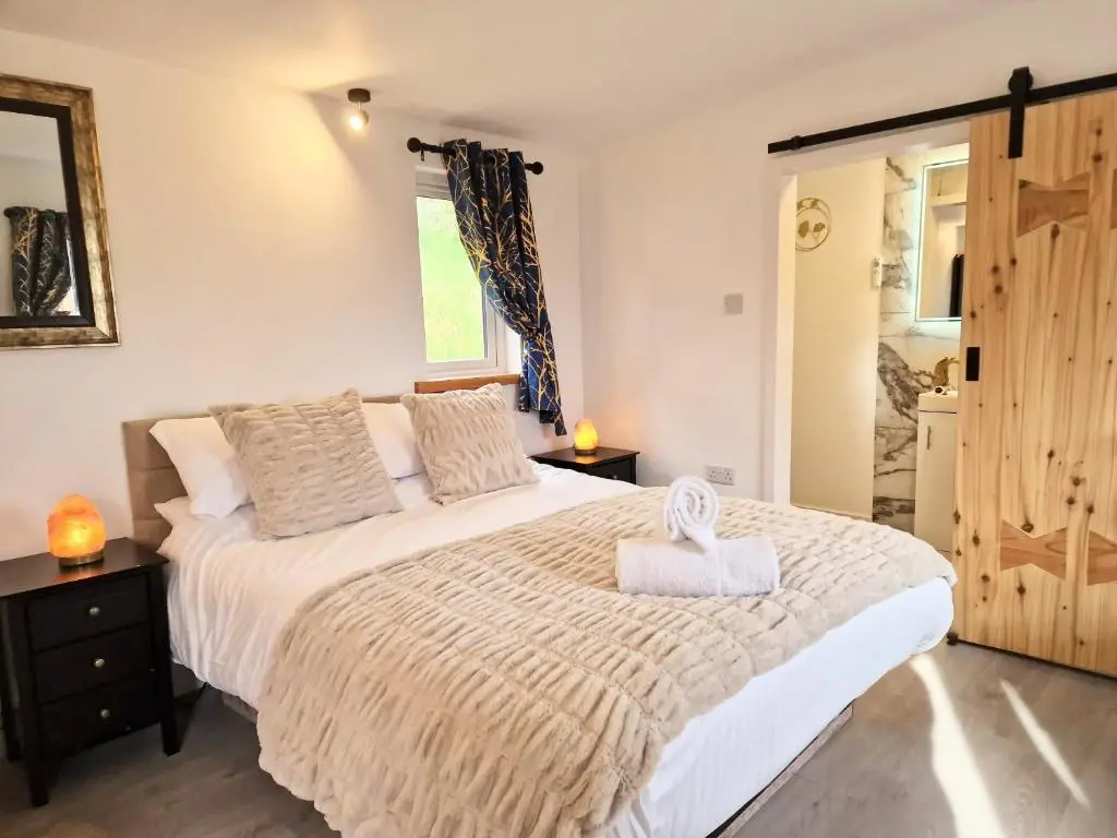 a bedroom with a large bed and a window at Kaoglen Fallow Pod - Luxury - Hot Tub - Pet Friendly in Blairgowrie
