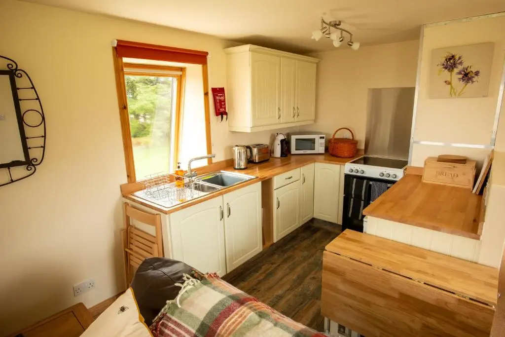 a kitchen with white cabinets and a sink at The High Croft in Rogart