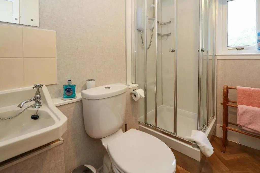 a bathroom with a toilet and a shower and a sink at Rose Cottage in Strathpeffer
