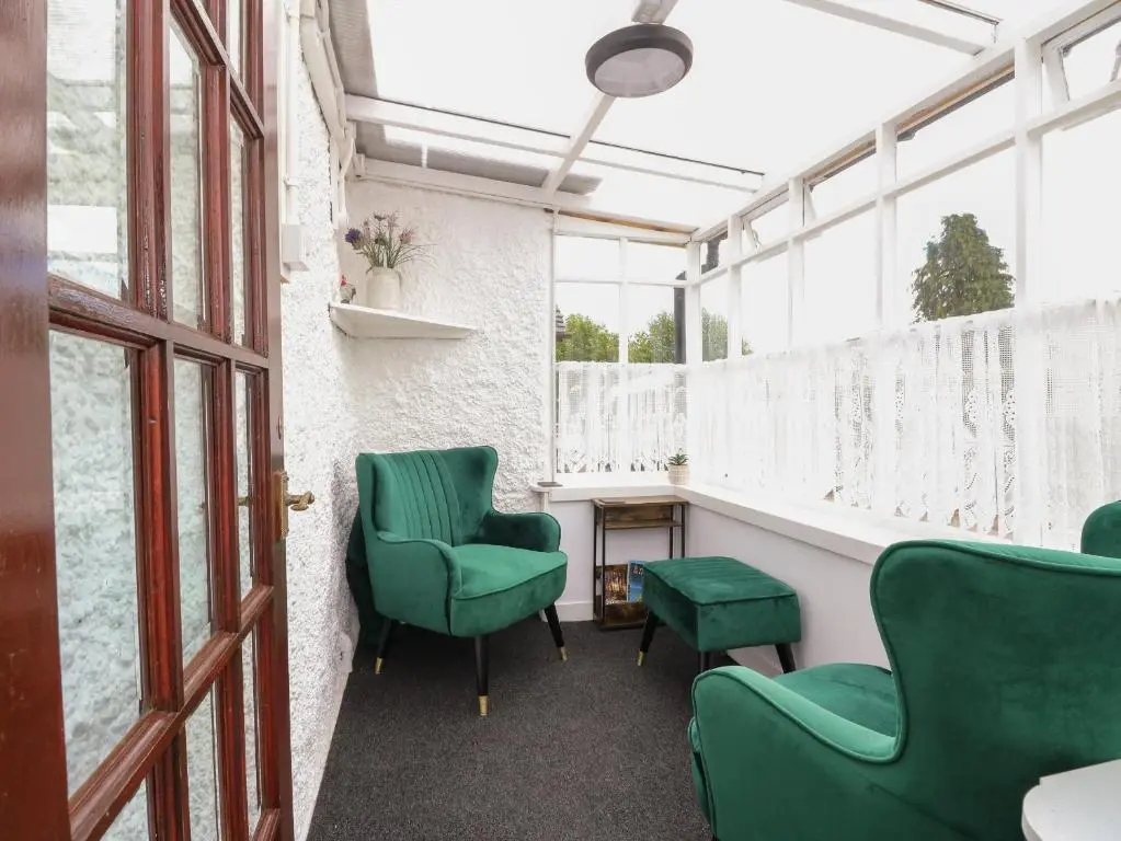 a waiting room with green chairs and windows at Rose Cottage in Strathpeffer