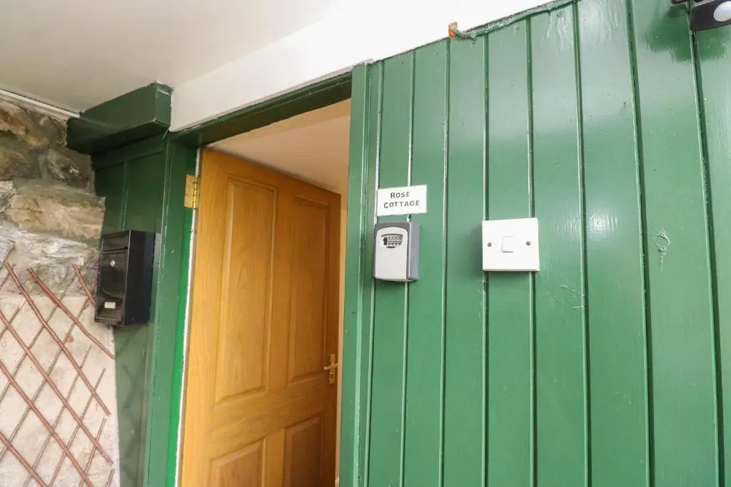 a green wall with a door and a sign that says exit at Rose Cottage in Strathpeffer
