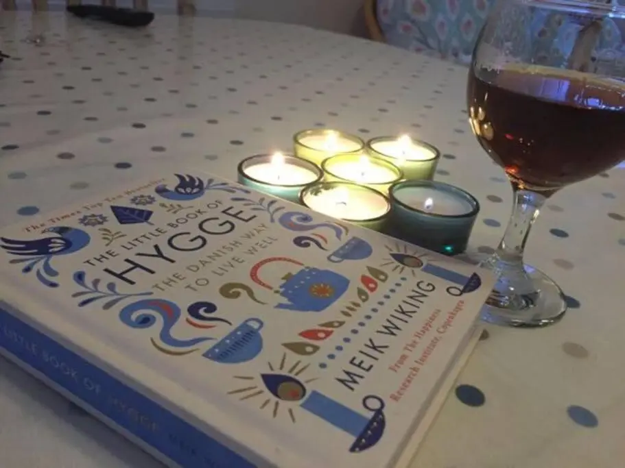 a book with candles and a glass of wine at Upper Corronich in Boat of Garten