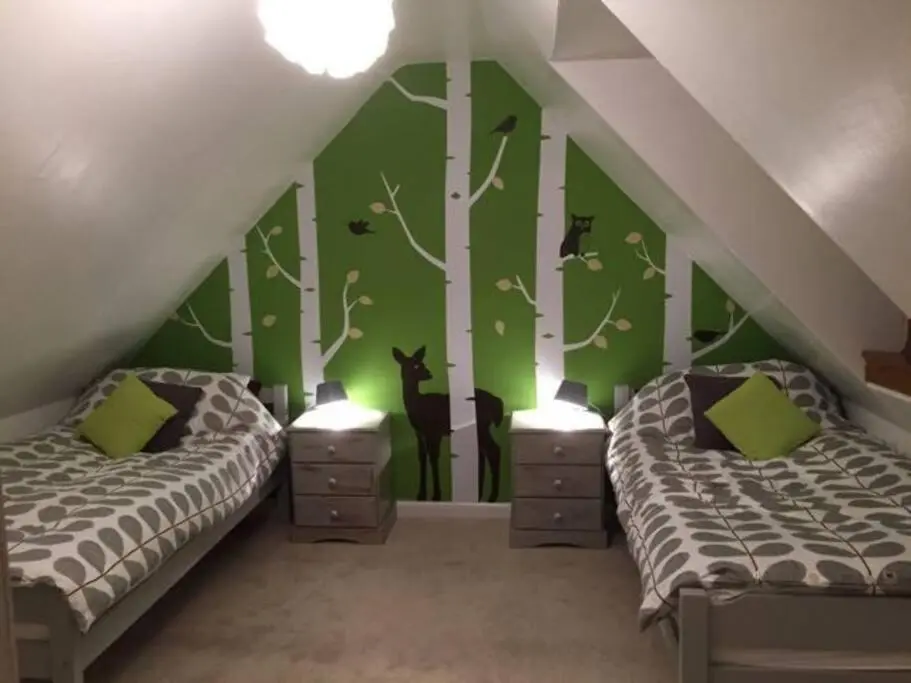 two beds in a room with green walls and trees at Upper Corronich in Boat of Garten