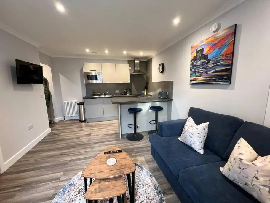 a living room with a blue couch and a table at Kingsmills Apartment in Inverness