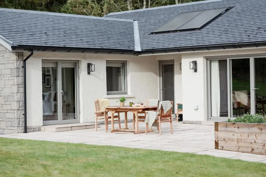 a patio with a table and chairs in front of a house at Culfoichbeg Lodge - Seasgair Lodges in Grantown on Spey