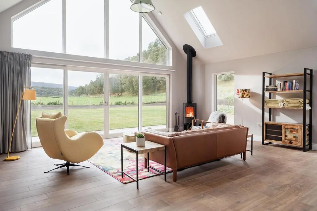 a living room with a couch and a chair and windows at Culfoichbeg Lodge - Seasgair Lodges in Grantown on Spey