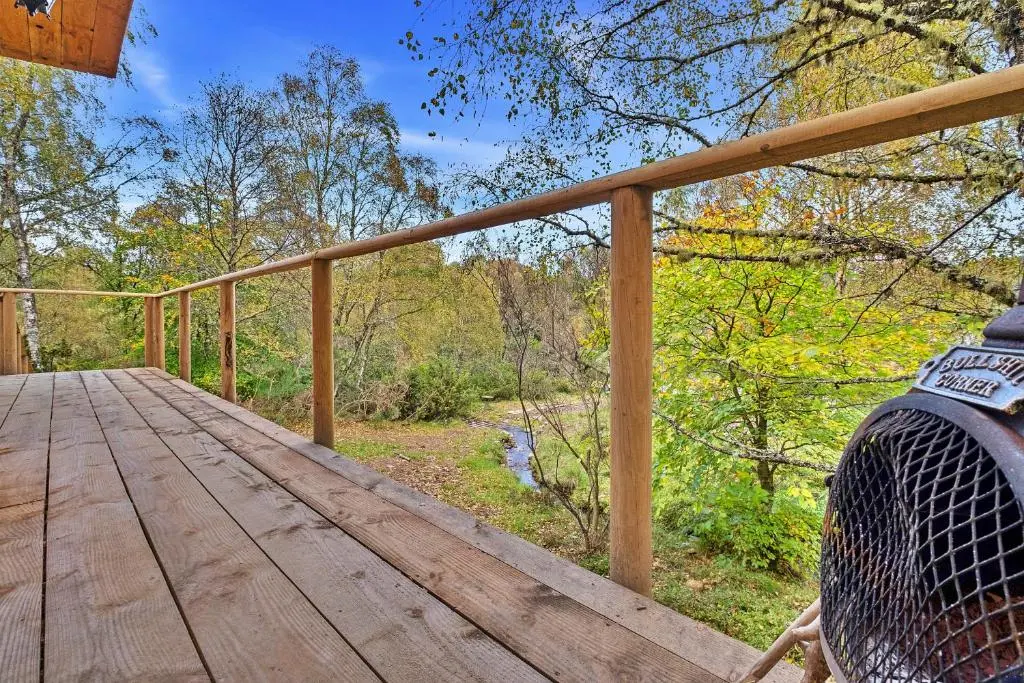 a wooden deck with a view of the woods at Finest Retreats - Cosagach Falls Cabin in Kiltarlty