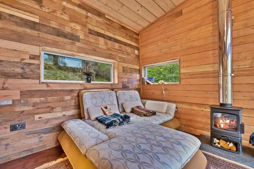 a living room with a couch and a stove at Finest Retreats - Cosagach Falls Cabin in Kiltarlty