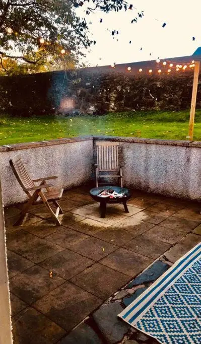 a patio with a chair and a bench in the rain at River Cottage in Turriff