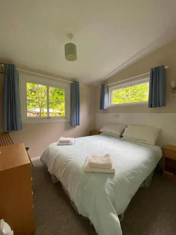 a bedroom with a large white bed with two towels on it at Baillie Chalet on Reelig Estate in Kirkhill