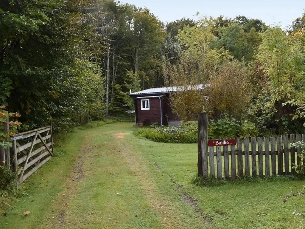 a fence in front of a small red shed at Baillie Chalet on Reelig Estate in Kirkhill