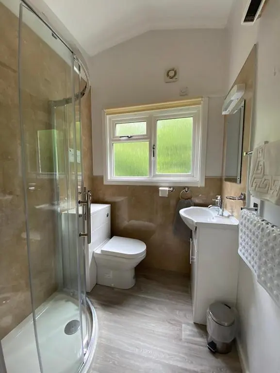a bathroom with a shower and a toilet and a sink at Satchwell Chalet on Reelig Estate - Dog Friendly in Kirkhill
