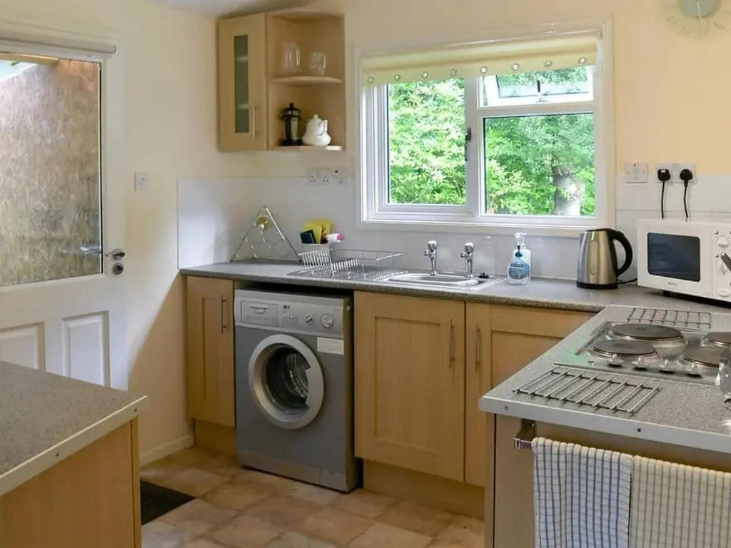 a kitchen with a sink and a washing machine at Satchwell Chalet on Reelig Estate - Dog Friendly in Kirkhill