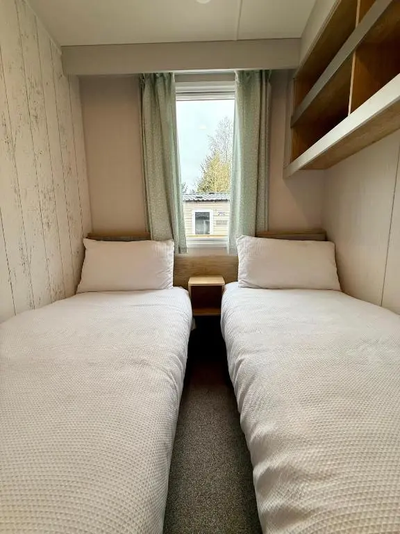 two beds in a small room with a window at The Malt Van - Beautiful, luxury static caravan in Aberlour