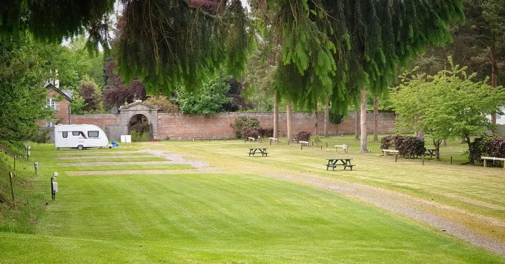 a park with benches and a trailer in the grass at The Ghillie's Van - Beautiful, luxury static caravan in Aberlour