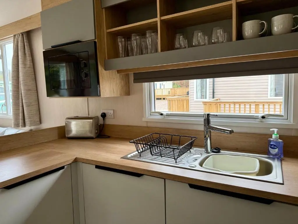 a kitchen with a sink and a window at The Ghillie's Van - Beautiful, luxury static caravan in Aberlour