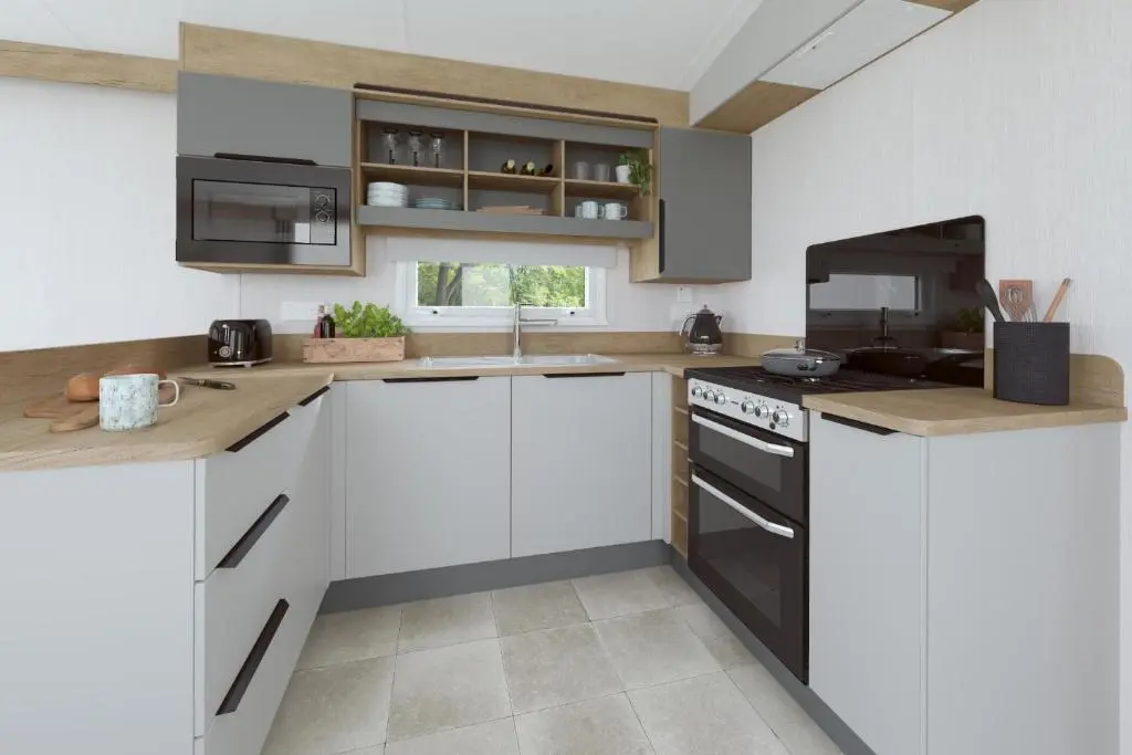 a kitchen with white cabinets and black appliances at The Cooper's Van - Beautiful, luxury static caravan in Aberlour