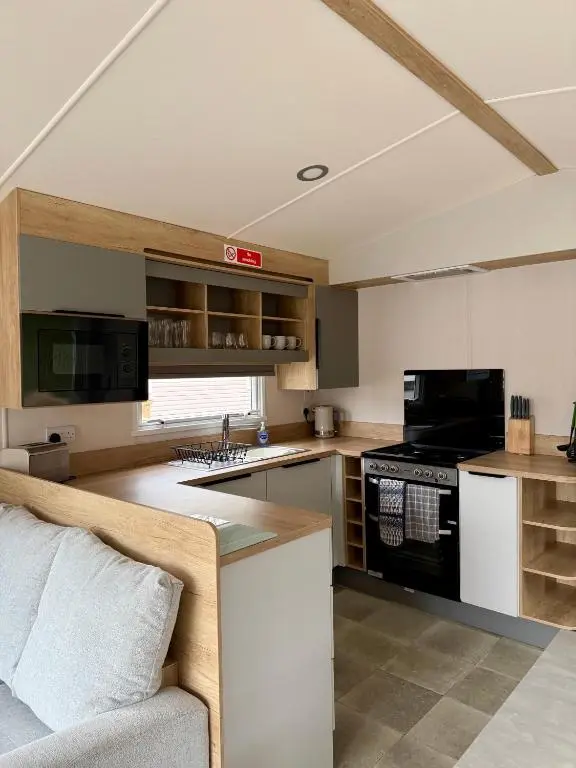 a kitchen with a couch and a stove top oven at The Cooper's Van - Beautiful, luxury static caravan in Aberlour