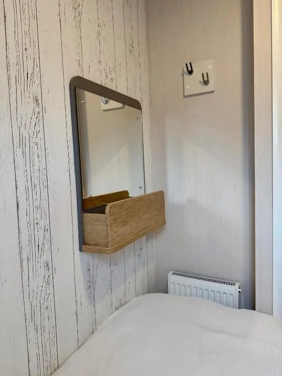 a mirror on a wall next to a bed at The Distiller\u2019s Van - Beautiful, luxury static caravan in Aberlour